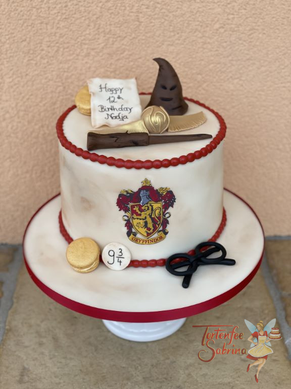 Geburtstagstorte Mädchen - Hogwarts Gryffindor Wappen ziert vorne die Torte, oben drauf liegt der goldene Schnatz.