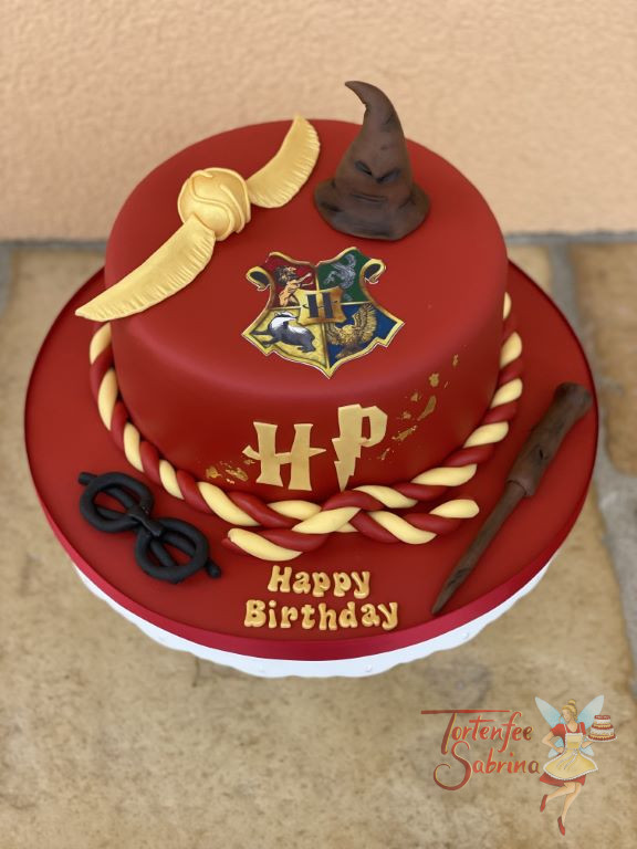Geburtstagstorte Erwachsene - Hogwarts in Rot, oben auf der Torte ist das Hogwarts-Wappen sowie der sprechende Hut und der goldene Schnatz.