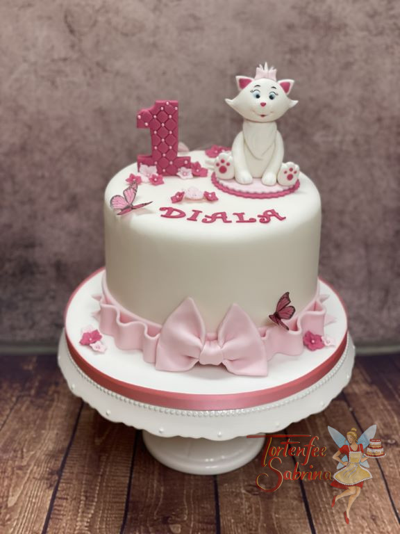 Geburtstagstorte Mädchen - Kätzchen auf der Decke, sitzt und lächelt von der schön verzierten Torte mit rosa Schleife.