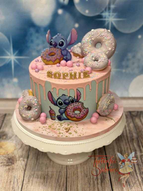 Geburtstagstorte Mädchen - Kleiner blauer Stitch sitzt oben auf der Torte und verschlingt die bunten Donuts mit Streusel.