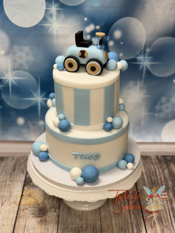 Geburtstagstorte Buben - Kleines blaues Rutschauto verziert ganz oben die Torte, welche zusätzich mit blauen Streifen erstrahlt.