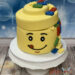 Geburtstagstorte Buben - Kopf voller Legosteine welche seitlich schon herausfallen, während uns das Gesicht die Zunge zeigt.