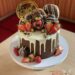 Geburtstagstorte Erwachsene - Marzipanbärchen auf dem Drip Cake welcher mit Süßigkeiten, Früchten und einem Cake-Topper verziert ist.