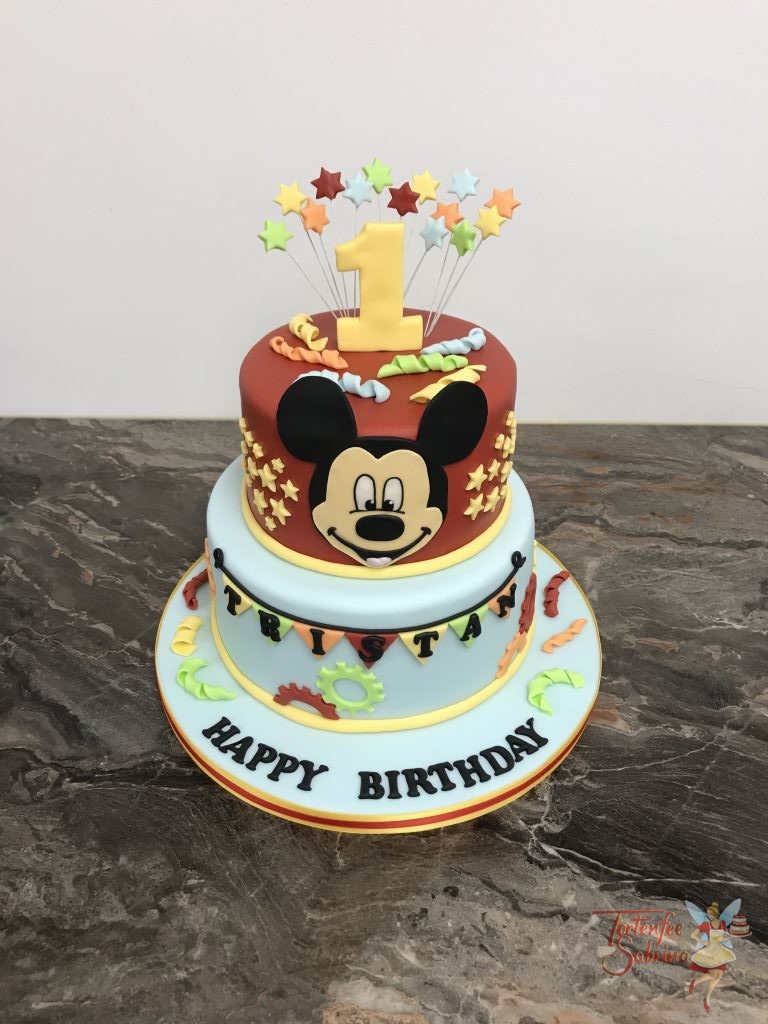 Geburtstagstorte Buben - Mickey Mouse and Stars. Die Torte ist verziert mit Sternen und Zahnrädern in den Farben rot, blau, orange und grün.