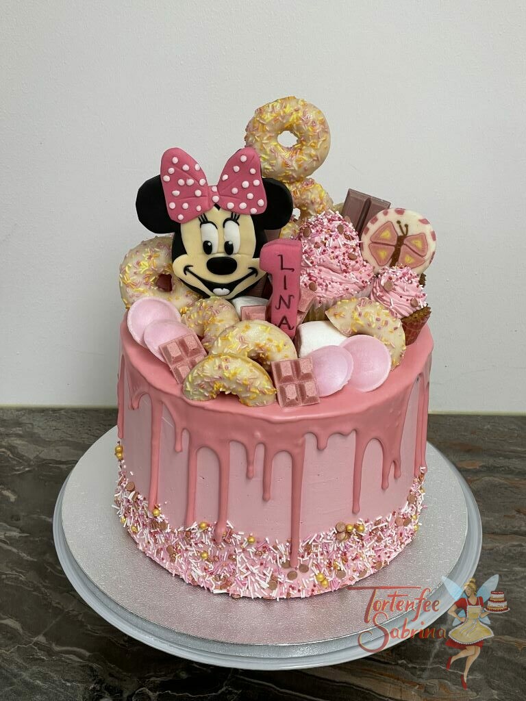Geburtstagstorte Mädchen - Minnie Mouse zwischen Süßem wie Dounts, Schokolade und Schleckern. Die Torte wurde mit einem rosa Drip verziert.