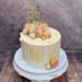 Geburtstagstorte Erwachsene - Orange Macarons verzieren auf dem aprikofarbenem Drip die Torte mit goldenem Caketopper.