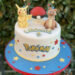 Geburtstagstorte Mädchen - Pikachu und Wuffels sitzen neben dem Pokeball auf der Torte, umgeben von vielen bunten Sternen.