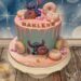 Geburtstagstorte Mädchen - Rosa Drip mit Stitch welcher sich über die unzähligen bunten Donuts auf der Torte.