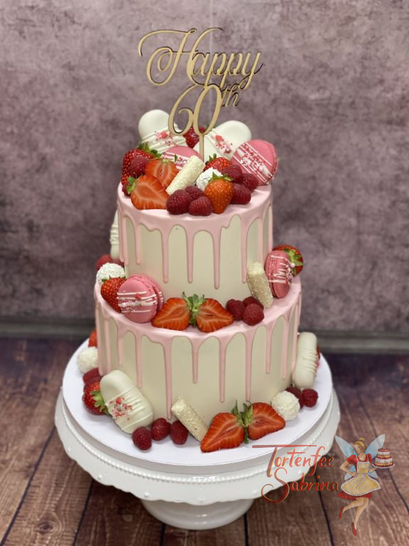 Geburtstagstorte Erwachsene - Rosa Süßigkeiten zieren neben roten Beeren die zweistöckige Torte mit Caketopper.