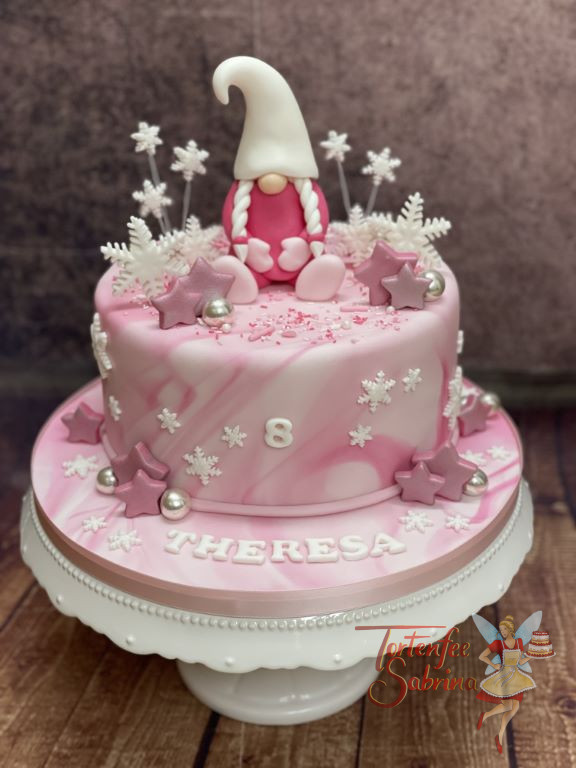 Geburtstagstorte Mädchen - Rosa Wichtelin mit großer Zipfelmütze und 2 Zöpfen sitzt auf der rosa-weiß Marbe-Effekt eingedeckten Torte.