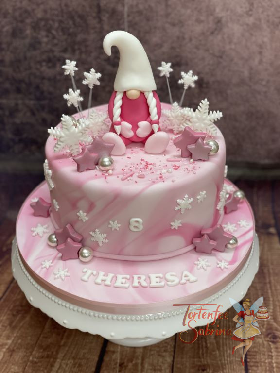Geburtstagstorte Mädchen - Rosa Wichtelin mit großer Zipfelmütze und 2 Zöpfen sitzt auf der rosa-weiß Marbe-Effekt eingedeckten Torte.
