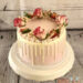 Geburtstagstorte - Rosen auf weißem Drip, die Torte wurde rosa eingestrichen und mit süßer Schokolade verziert.
