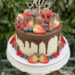 Geburtstagstorte Erwachsene - Rote Früchte und Schokolade in Form von Süßigkeiten zieren neben dem Cake-Topper den Drip Cake.