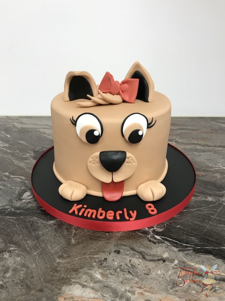Geburtstagstorte Mädchen - Runder Hund, diese Torte wurde als Hundekopf verziert und schaut süß mit seinen großen Augen und der roten Schleife.