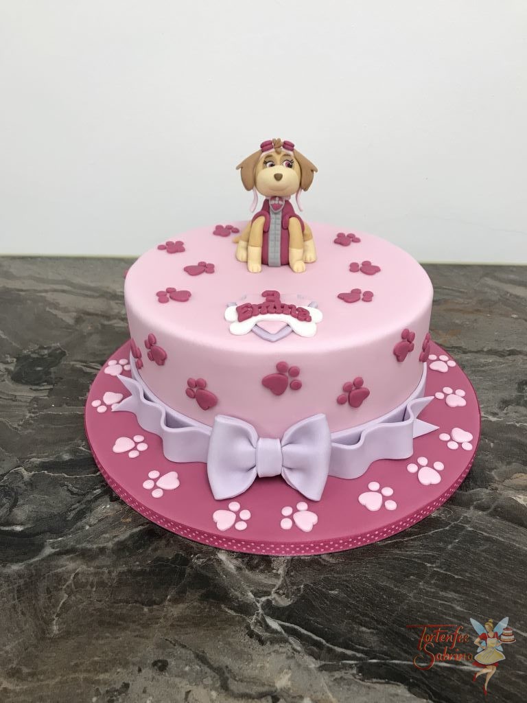 Geburtstagstorte Mädchen - Skye ganz in rosa. Hier zeigt sich der Fellfreund auf einer ganz rosa Torte mit Pfotenabdrücken und Schleife.