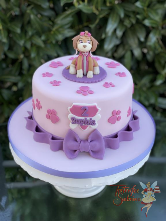 Geburtstagstorte Mädchen - Skye mit rosa Pfötchen sitz oben auf der rosa Torte, den unteren Abschluß bildet eine lila Schleife.