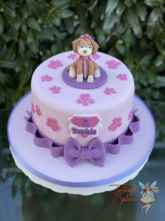 Geburtstagstorte Mädchen - Skye mit rosa Pfötchen sitz oben auf der rosa Torte, den unteren Abschluß bildet eine lila Schleife.
