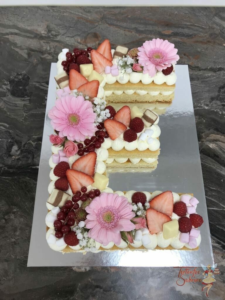Geburtstagstorte - Süßes blumiges "E" wurde mit rosa Blumen, Erdbeeren, Himbeeren, Ribiselm und verschiedenen Süßigkeiten.