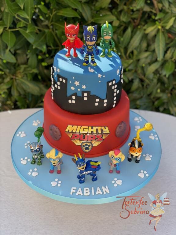 Geburtstagstorte Buben - Superhelden Migthy Pubs und PJ Maske gemeinsam auf der Torte mit dunklen Gebäudesilhouetten.