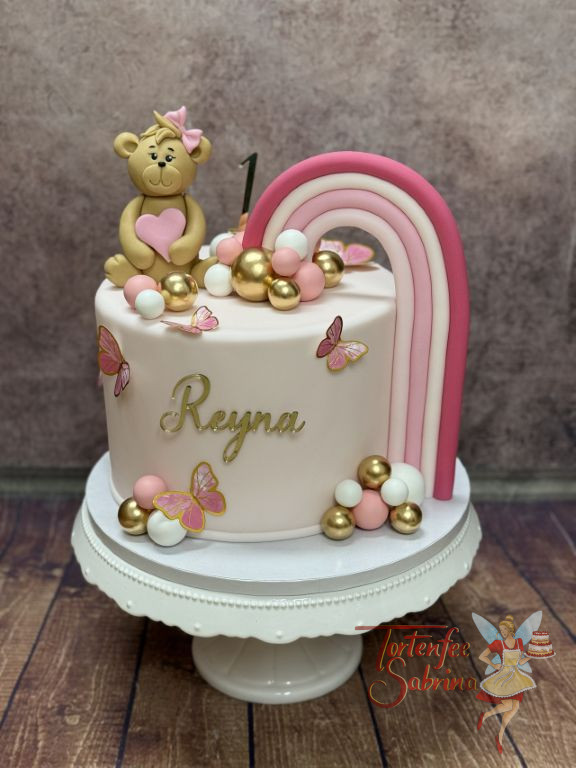 Geburtstagstorte Mädchen - Weiß-Rosa Regenbogen verziert neben den kleinen süßen Teddybären mit Schleife die Torte.
