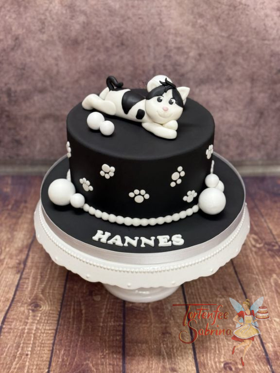Geburtstagstorte Buben - Weiß-Schwarzes Kätzchen liegt ganz verspielt auf der Torte und seitlich sind die Pfotenabdrücke.