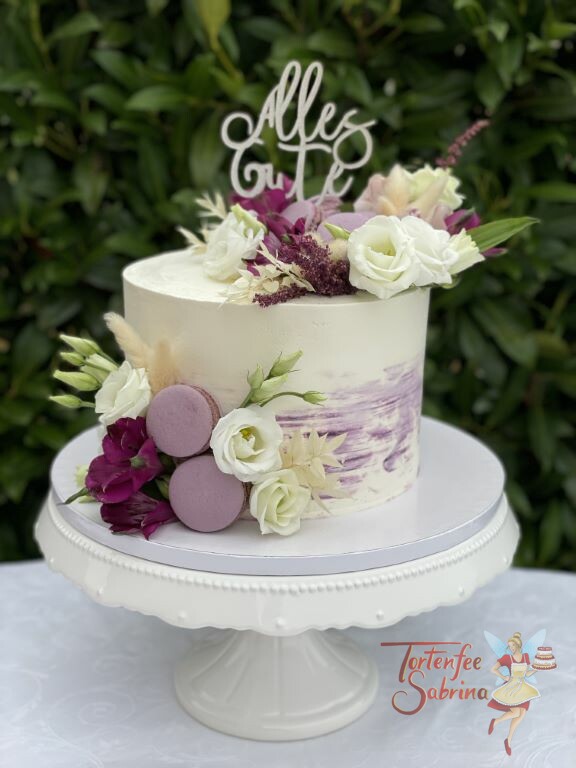 Geburtstagstorte Erwachsene - Weiße und lila Blumen zieren diese schön geschmückte Torte, ebenfalls auf der Torte sind lila Makronen.