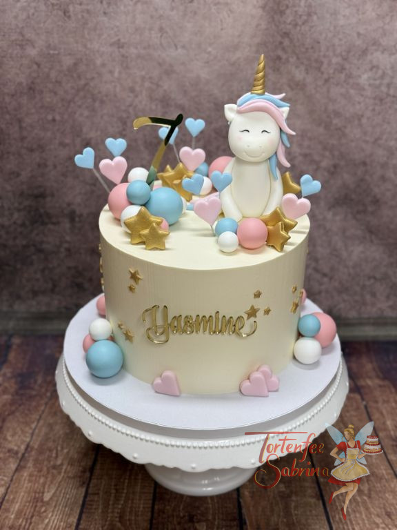 Geburtstagstorte Mädchen - Weißes Einhorn mit blau-rosa Mähne sitzt ganz oben auf der Torte neben Herzen, Sternen und dem Caketopper.