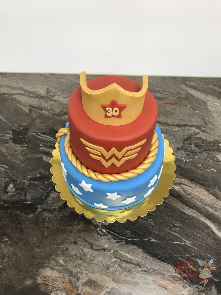 Geburtstagstorte Erwachsene - Wonderwoman mit Korne, Kordel und Schriftzug in gold. Der untere Teil der Torte ist blau mit Sternen.