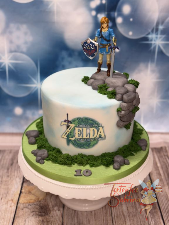 Geburtstagstorte Buben - Zeldas Link steht ganz oben auf der Torte, mit Schild und Schwert in der Hand und vorne das Logo.