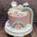 Geburtstagstorte Mädchen - Zwei Regenbogen mit ein paar Wolken verzieren die Torte neben dem glücklichen Einhorn ganz oben.
