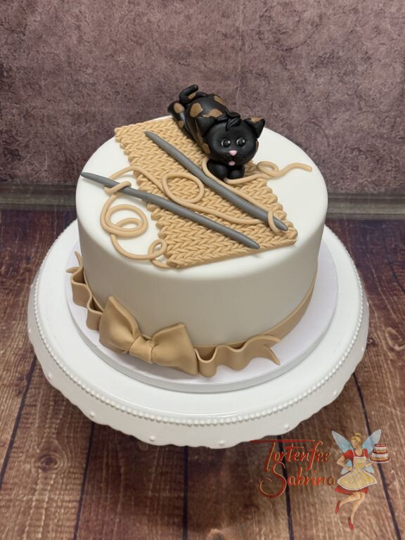 Geburtstagstorte Erwachsene - Zwei Stricknadeln und die Wolle liegen auf der Torte wo schon das Kätzchen wartet.