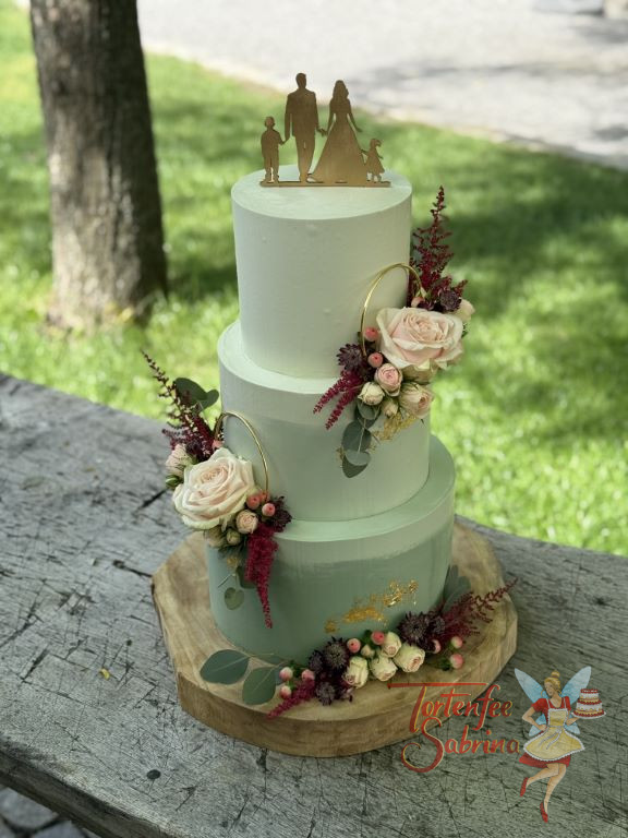 Hochzeitstorte - Ab ins Grüne heißt es für das Brautpaar mit ihren Kindern welche ganz oben die dreistöckige Torte als Caketopper zieren.