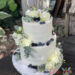 Hochzeitstorte - Beeren und Eukalyptus verzieren neben den weißen Rosen die Torte und ganz oben ist der Caketopper aus Holz.