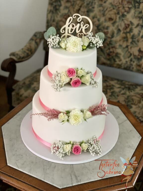 Hochzeitstorte - Blumen mit rosa Band als Abschluß für jede einzelne Torte, ganz oben auf der Torte ist der Cake Topper mit Blumen.