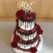 Hochzeitstorte - Blumen und Beeren, dieser Drip Cake mit dunkler Schokolade wurde mit roten Rosen und verschiedenen Beeren verziert.