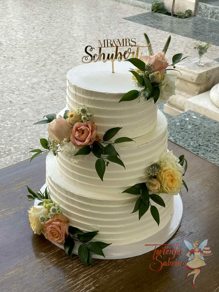 Hochzeitstorte - Blumen mit Rillen und einem goldenen Cake-Topper. Die Torte wurde mit Rosen in den Farben gelb, rosa und weiß verziert.