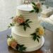 Hochzeitstorte - Blumen mit Rillen und einem goldenen Cake-Topper. Die Torte wurde mit Rosen in den Farben gelb, rosa und weiß verziert.