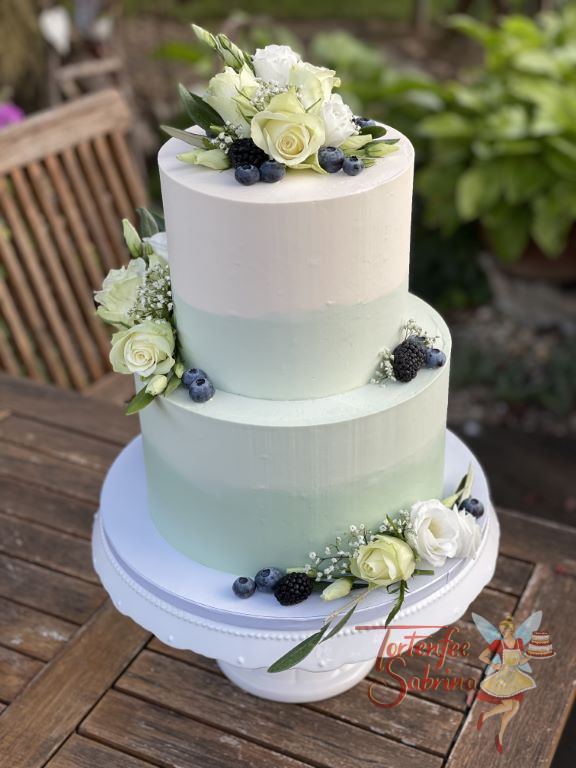 Hochzeitstorte - Dunkle Beeren auf grün-weiss eingestrichener Torte. Die zwei Stöcke zieren weiters noch Blumen.