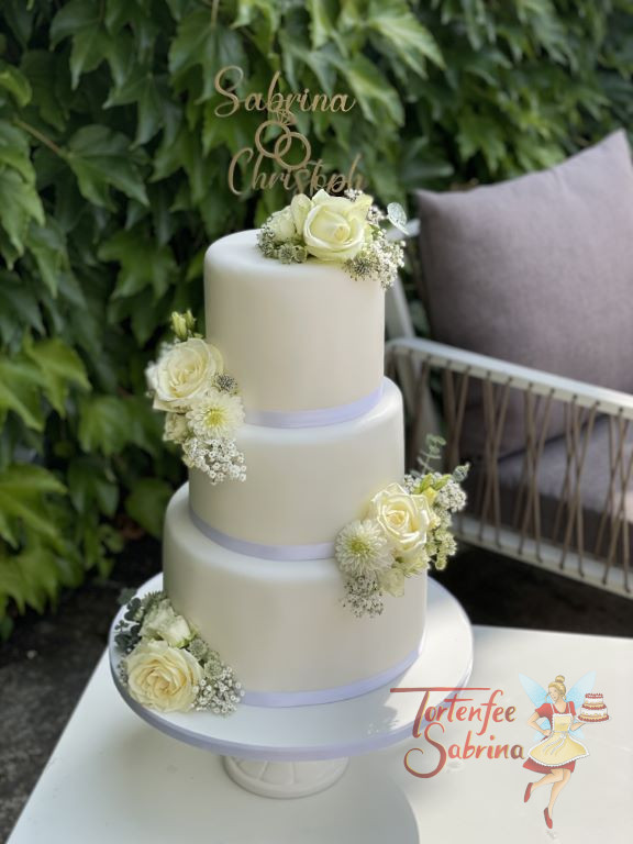 Hochzeitstorte - Edel in weiß erscheint hier die Torte, der Abschuß wurde mit zarten Bändern hergestellt und mit Blumen geschückt.