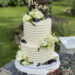 Hochzeitstorte - Exakte Rillen verzieren seitlich die Torte, zusätzlich schmücken noch Blumen und Caketopper die Torte.