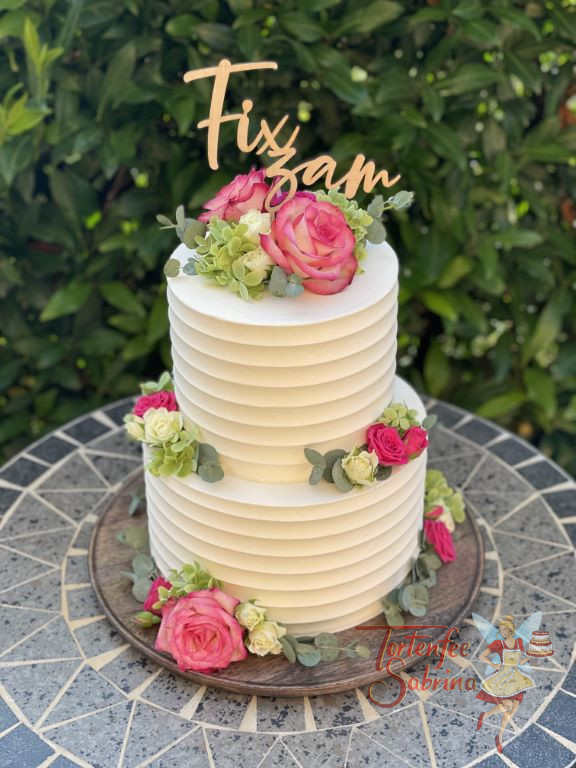 Hochzeitstorte - Exaktes Rillenmuster verziert die zweistöckige Torte, welche zusätlich noch mit Blumen dekoriert ist.