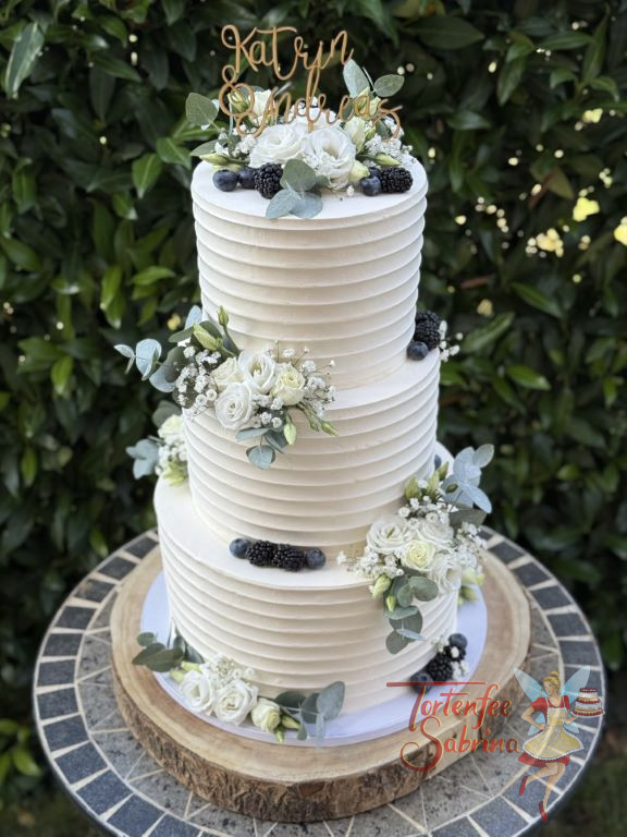Hochzeitstorte - Feine Rillen verzieren alle drei Etagen der Torte, zusätzlich sind noch Blumen, Beeren und ein Caketopper dabei.