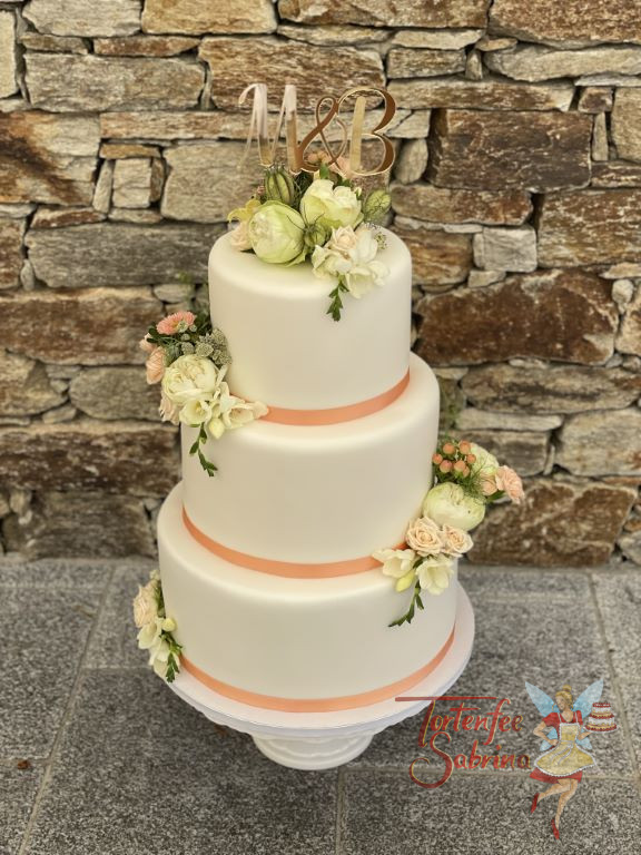 Hochzeitstorte - Glänzende Buchstaben in Rosegold verzieren neben dem üppigen Blumenschmuck und Bändern die Torte.