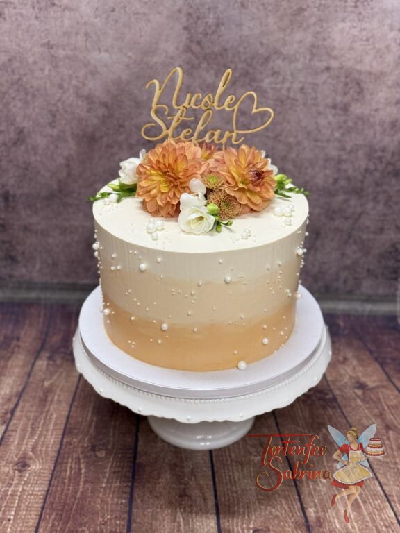 Hochzeitstorte - Große und kleine Perlen verzieren neben den Blumen und dem Caketopper die mehrfärbige Torte.