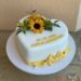 Hochzeitstorte - Herz mit Sonnenblumen sowie Name und Datum der Hochzeit. Der untere Abschluß ist eine gelbe Schleife.