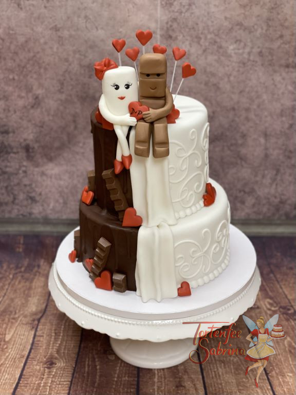 Hochzeitstorte - Kinderriegel mit Herzen auf der Torte, welche zur Hälfte ein Drip Cake ist und auf der anderen Hälfte weiß verziert wurde.