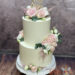 Hochzeitstorte - Kleine rosa Blüten verzieren neben den großen Rosen die weiß eingestrichene zweistöckige Torte mit Caketopper.