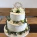 Hochzeitstorte - Love mit Blumengirlande, die Torte wurde mit einem Rillenmuster eingestricken und einem Topper gekrönt.