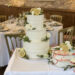 Hochzeitstorte - Olivenzweige treffen auf Zitronen und weiße Blumen, in diesem Design wurde die Haupttorte und die Beitorte verziert.