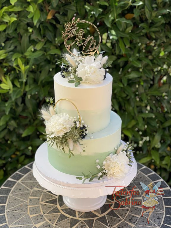 Hochzeitstorte - Ring in goldener Farbe verziert die zweistöckige Torte mit Farbverlauf von grün auf weiss.